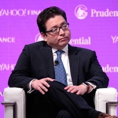 A man in a dark suit and glasses sits in a white chair on a stage with a purple backdrop featuring 'YAHOO! FINANCE' and 'Prudential' logos.