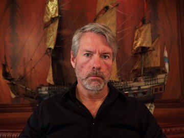 The post shows a photo of Michael Saylor, the Bitcoin advocate and MicroStrategy co-founder, pictured with gray hair and a beard against a backdrop featuring a model sailing ship.