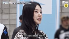 A young woman with long dark hair stands in what appears to be an airport or transit area, with a Mnet logo and broadcast graphics visible on screen. The caption "NOZE soon on #SDF" suggests this is a teaser of the dancer/celebrity soon appearing on a show, matching the broadcast styling shown.