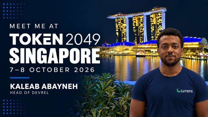A promotional graphic announces 'MEET ME AT TOKEN 2049 SINGAPORE' on '7-8 OCTOBER 2026' featuring Kaleab Abayneh, Head of DevRel at Lumera, with the Marina Bay Sands in the image background.