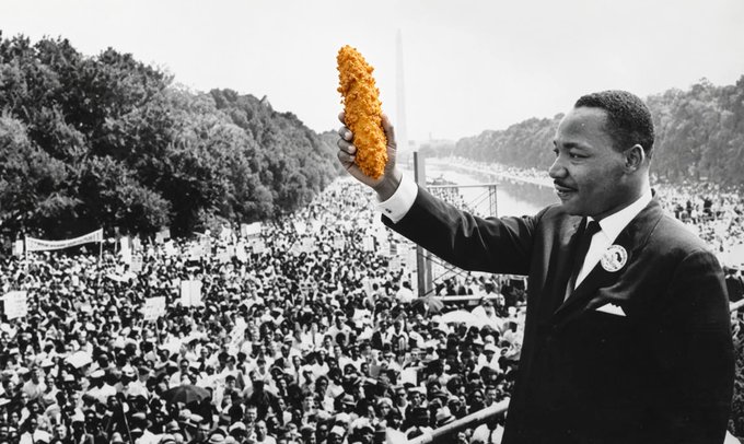 A black-and-white historical photo of Martin Luther King Jr. speaking to a massive crowd at the Lincoln Memorial has been humorously edited so he is holding up a piece of fried chicken instead of gesturing with his empty hand.