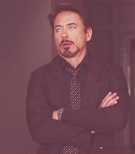 A stylized portrait of actor Robert Downey Jr. wearing a black suit, polka dot tie, and sunglasses, with his arms crossed.