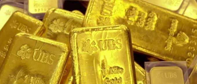 A close-up view of stacked UBS-branded gold bars, with markings indicating 1kg fine gold 999.9.