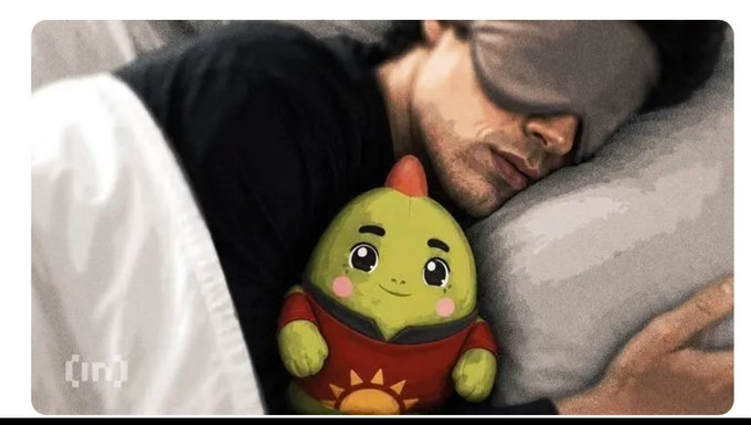 A man wearing an eye mask sleeping in bed while cuddling a green avocado plush toy with a sad tear, featuring an '(in)' logo in the corner.