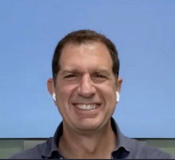 The image shows a smiling man wearing white wireless earbuds and a blue collared shirt, appearing to be on a video call against a blue background. The "RH bridgers rn" caption suggests he is one of the Robinhood employees being interviewed on the "Buried" streaming series hosted by Rob Hoffman, where Robinhood employees share their experiences.