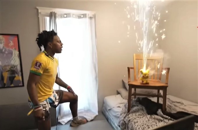 A person wearing a yellow jersey dancing in a bedroom while a Pikachu figure on a wooden chair shoots out sparks like a fountain.