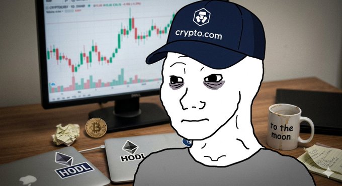 A Wojak-style character wearing a 'crypto.com' cap sits at a desk with a trading chart on the monitor, a Bitcoin coin, and a coffee mug reading 'to the moon.'