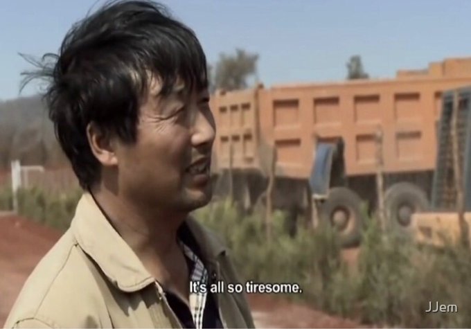 A weathered man with disheveled hair stands outdoors near a large orange dump truck, captioned "It's all so tiresome." The image conveys a sense of exhaustion and weariness, humorously pairing with the post's theme of one person with an X account causing widespread exhaustion and chaos.