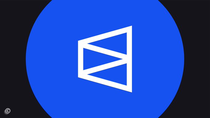 A blue circle displays a white stylized "E" logo with geometric triangular elements, set against a dark background, with a small copyright symbol in the bottom left corner. The image relates to the post as it appears to be the logo or branding associated with Polymarket, the crypto prediction platform mentioned in the news about the lawsuit.