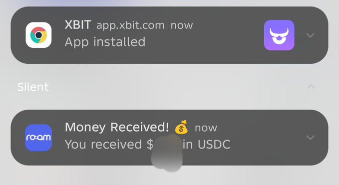 Two phone notifications confirm an XBIT app installation and a money receipt in USDC via the Roam app, illustrating the post's claim of getting paid in USDC directly to Roam after successful predictions on XBIT.