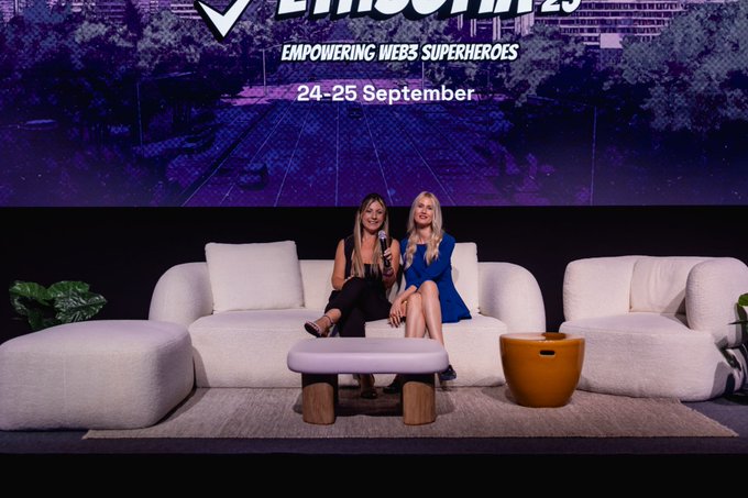 Two women sit on white sofas on a stage at a conference, with a screen behind them reading 'ETHCC 25', 'EMPOWERING WEB3 SUPERHEROES', and '24-25 September'.