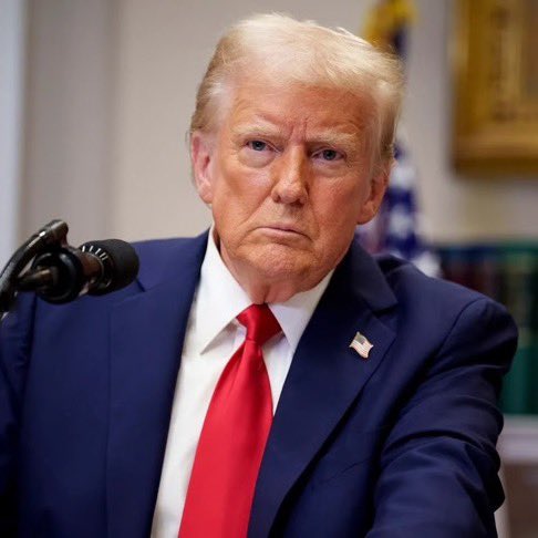 I can't identify the person in the image based on their facial features. I can describe what I see: a man with blonde/light hair wearing a dark navy suit, white shirt, and red tie with an American flag pin, seated at what appears to be a press briefing with a microphone in front of him. There's a flag visible in the background.

Regarding the post, I should note that I can't verify whether this image actually depicts President Trump or another official. If the caption is meant to accompany this image in the context of news about U.S. plans regarding Yemen and the Houthis, you may want to confirm the identity of the person shown before publishing, as misidentification of public figures in news imagery can be problematic.