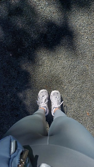 The image shows a person's feet wearing white sneakers, standing on a gray pavement or road with their legs crossed. They are positioned at the bottom of the frame, giving an upward view of them. The photo appears to be taken during daytime hours, as there is sunlight present in the scene. The caption "GM CT small steps every day they add up happy thursday" suggests that the person might have been taking a walk or engaging in some form of physical activity recently.

The image seems to be related to the post about walking for happiness, as it captures a moment where someone is enjoying their time outdoors and possibly incorporating exercise into their daily routine. The caption emphasizes the importance of small steps towards a healthier lifestyle, which can contribute to overall well-being and happiness.