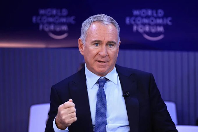 A middle-aged man with gray hair, wearing a dark suit and blue patterned tie, speaks while gesturing with a clenched fist at a World Economic Forum event. The accompanying text appears unrelated to the image, referencing Citadel and financial markets, as the man pictured does not match that context.