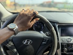 A driver's hand rests on the steering wheel of a Hyundai, symbolizing a day in motion. The image reflects the post's narrative of a balanced day—mixing small spending, gains from crypto/NFT trading, and a game of football—capturing the forward momentum toward a better week ahead.