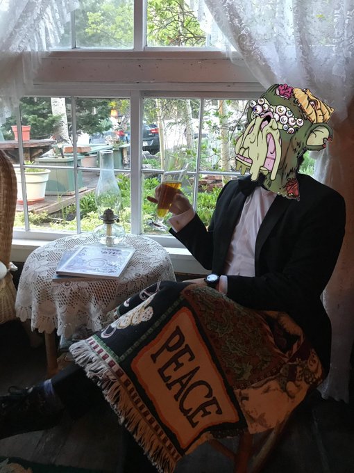 A person wearing a Bored Ape Yacht Club NFT mask sits in a tuxedo by a window, holding a drink, with a "PEACE" tapestry draped over their lap. The image visually embodies the post's theme of pride and membership in the exclusive Bored Ape Club community, blending Web3 identity with a refined, almost surreal lifestyle aesthetic.