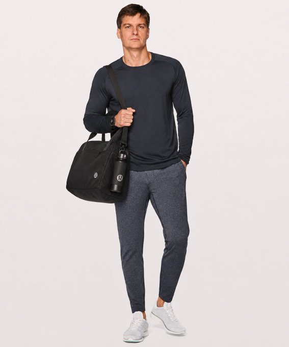 A relaxed man in athletic wear stands in a Lululemon duffel bag featuring the brand's logo, holding a matching Lululemon water bottle. The image cleverly pairs with the caption by presenting someone who appears composed and casually dressed—with what seems to be a calm pre-gym look—just before a hypothetical market "liquidation," playing on the contrast between physical fitness routines and the calm before a financial collapse.