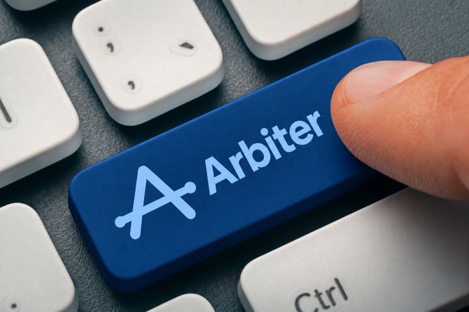 A close-up of a finger pressing a blue keyboard key labeled 'A Arbiter' next to a 'Ctrl' key.