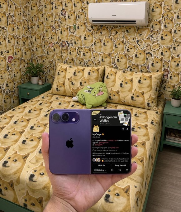 A hand holds up a purple iPhone displaying a Twitter page for the '#1 Dogecoin Wallet' (MyDoge), set against a bedroom with walls, bedding, and pillows covered in repeating Shiba Inu doge meme faces.