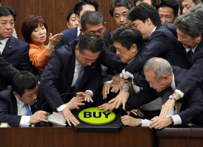 Japanese politicians in suits crowding around and pressing a large green 'BUY' button, parodying meme stock culture with what appears to be Shinzo Abe among them.