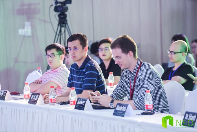 A panel of judges sits at a table with name placards reading "Adam" and others in Chinese characters, likely at an early Binance event or pitch competition where startup founders would have presented their projects. This throwback image showcases Binance's early community engagement during the company's nascent stage, before it became the world's largest cryptocurrency exchange.