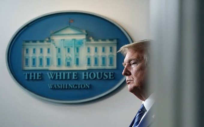 A man in a suit stands in profile next to the White House seal, which reads "THE WHITE HOUSE WASHINGTON," as he prepares to attend a crypto meeting at the White House.