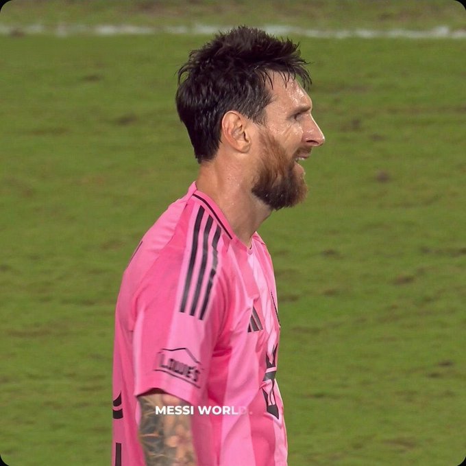 A side profile of football player Lionel Messi in a pink Inter Miami jersey on a green field, with a 'MESSI WORLD' watermark.