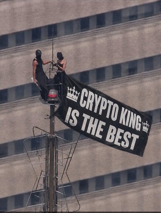 Two individuals unfurl a banner that reads "CRYPTO KING IS THE BEST" atop a structure against a building. This scene, likely a protest or stunt, shares a thematic link to the "Good night." post by implying the end of a day's hustle or a final declaration before winding down.