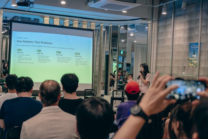 A woman in a beige outfit speaks into a microphone during a presentation about 'One Platform, Four Products' (Kakao Pro, Kakao API, Kakao MCP, Kakao Studio) to an audience, with one attendee recording on a smartphone.