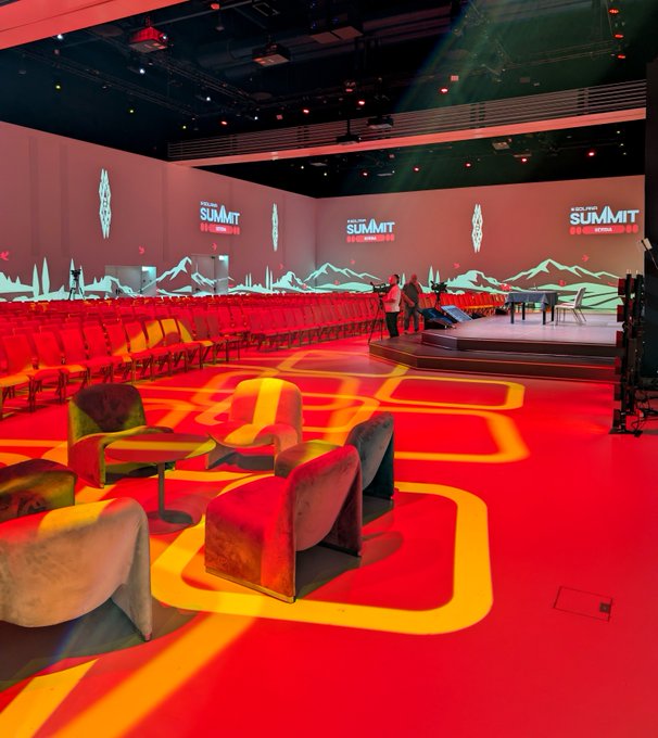 A nearly vacant auditorium awaits the start of the "Solana Summit" event, with only a few staff members visible amid hundreds of empty red seats and lounge chairs bathed in dramatic red lighting—visually confirming the post's quip about the disappointing turnout.