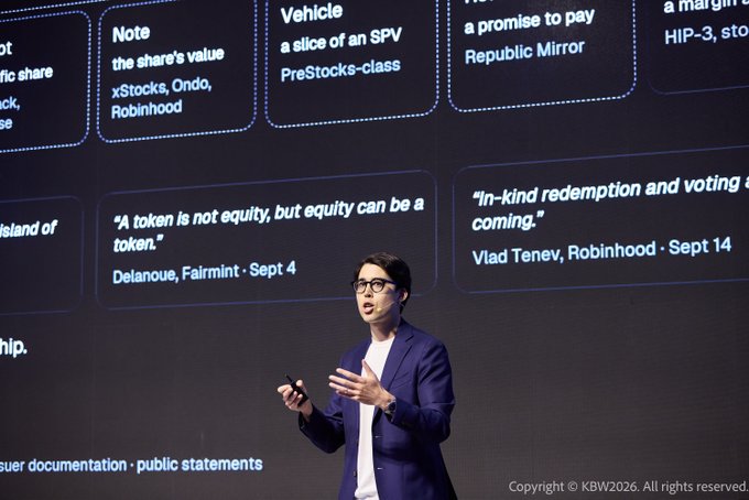 A man in a blue blazer giving a presentation on stage with a slide behind him displaying quotes about tokens and equity from Delanoue (Fairmint) and Vlad Tenev (Robinhood).