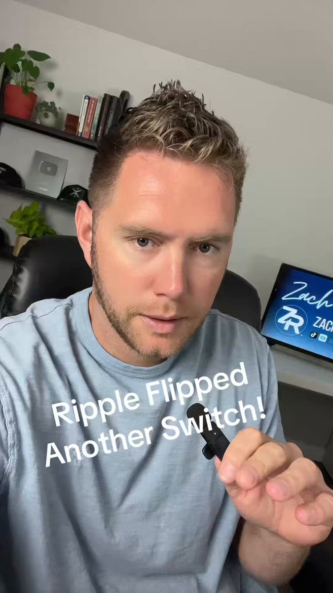 The image shows a man wearing a blue shirt holding a black electronic device, possibly an electronic cigarette or e-cigarette, with the words "Ripple still delivering utility and adoption despite market conditions" written above him. The man appears to be posing for a photo while holding the device in his hand.