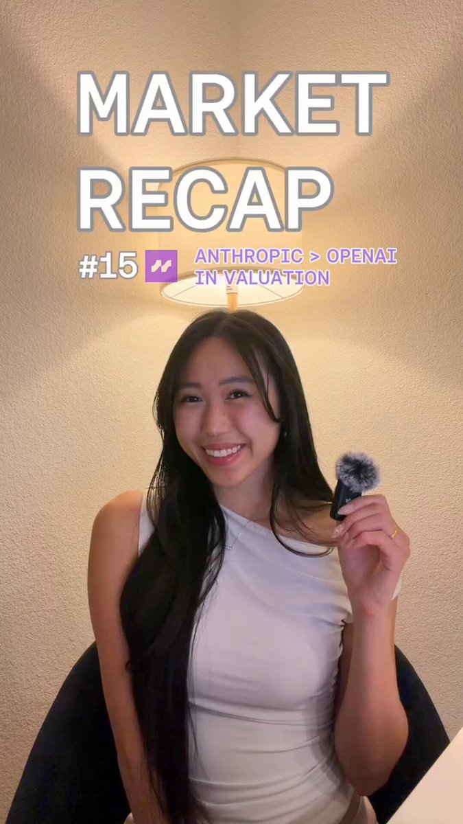 The image features a woman with long black hair holding up a makeup brush or hairbrush as if posing for a picture. The setting appears to be indoors, possibly in an office space or studio environment. Above her head, there is text that reads "Market Recap", which could indicate a recent market event or analysis conducted by someone else. In the background, another person can be seen, but their role and significance are not clear from the image alone.