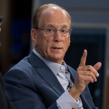 A man in a dark suit jacket, light blue checkered shirt, and glasses gestures with a pointed finger while speaking, likely during a televised interview or panel discussion. The post suggests this image relates to a BlackRock executive advocating for the Crypto Clarity Act to be passed by the U.S. Senate.