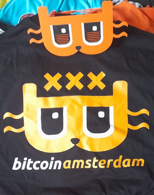 A black t-shirt with an orange cat graphic and the text 'bitcoin amsterdam'.