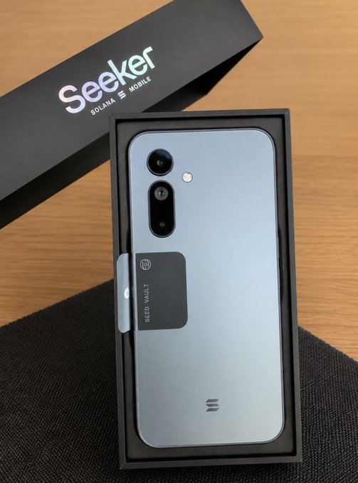 The image shows a Seeker (Solana Mobile) smartphone in its packaging, featuring a "Seed Vault" hardware wallet component on the back, along with "SOLANA" and "Seeker" branding on the box—showcasing the crypto-integrated device referenced in the post.