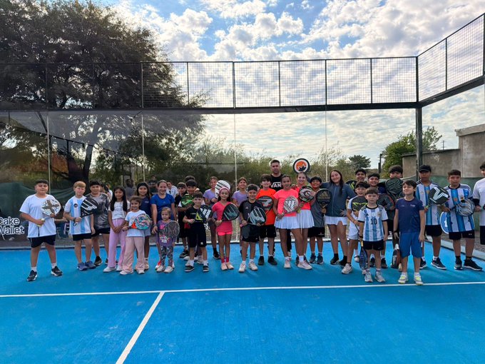 The image shows a group of people standing together, all holding tennis rackets. They are posing for a photo at a tennis court with a blue background. The text "We greet the @monero community present at @MoneroKon from the cradle of the circular economy in xmr! Hand in hand with @vikrantnyc and @cakewallet always!" is visible, which suggests that this group of people might be participating in or supporting an event related to tennis or sustainability. The presence of multiple tennis rackets indicates their involvement in the sport, while the blue background adds a vibrant touch to the scene.