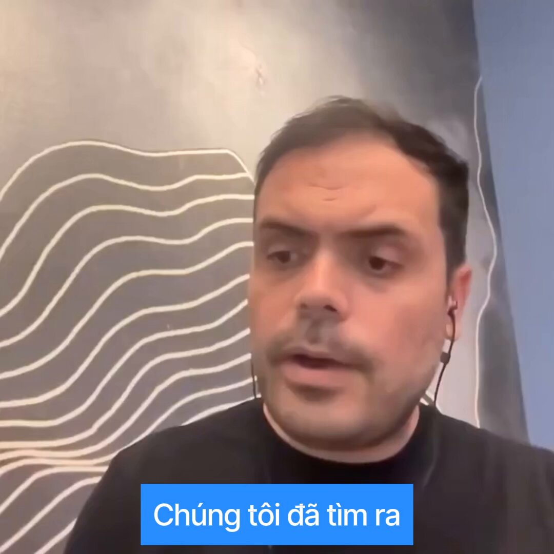 The image features a man wearing headphones, with his face partially visible as he speaks into them. The background of the photo shows a gray wall with white lines running across it. The caption below the image reads "Chung tại da tim ra" which translates to "I am talking".