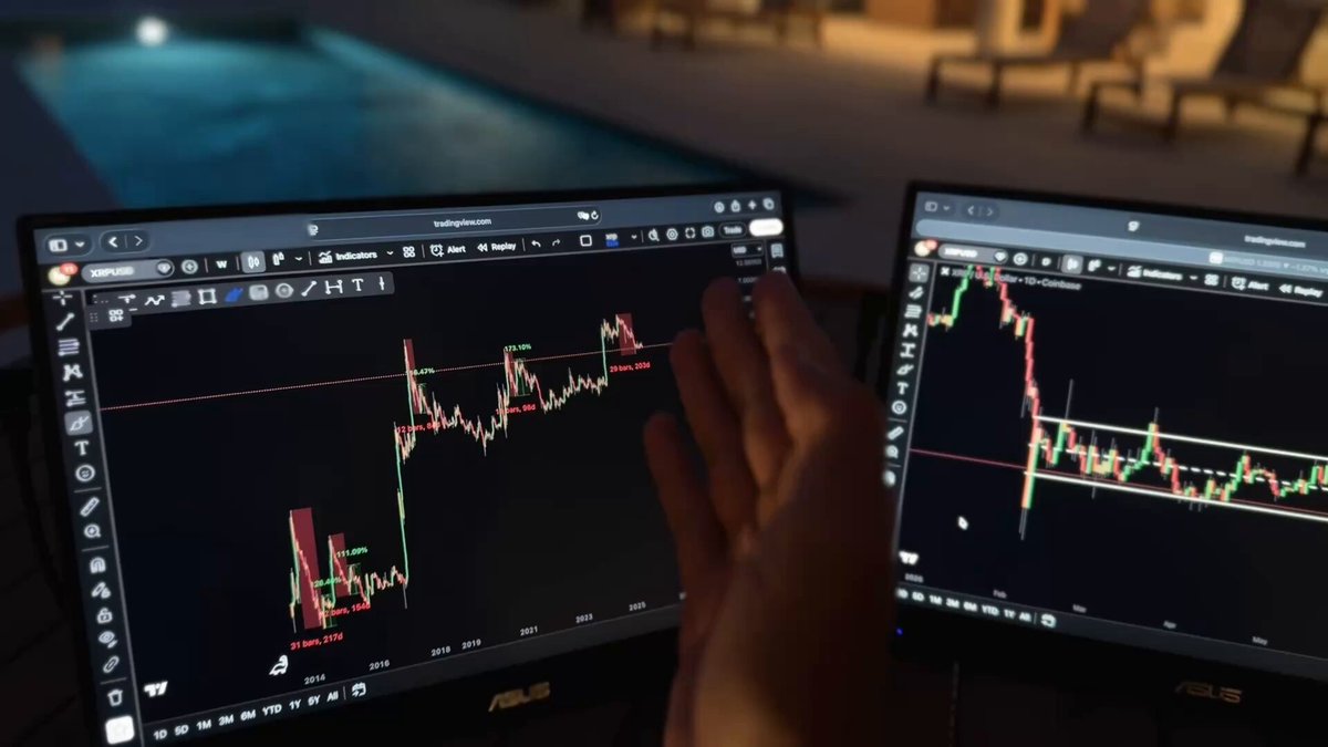 The image shows a pair of computer monitors side by side with a person's hand resting over one of them, as if they're about to press an unseen keyboard. The screens display stock market charts that include major cryptocurrency names such as Bitcoin and Etherium. The text on the image suggests that there is news being shared in the space, which may be related to cryptocurrency or the financial markets. This scene appears to represent a moment of interest or action around these topics.