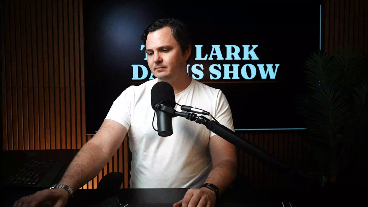 The image features a man talking into a microphone, which appears to be related to the Bitcoin charts since there are mentions of Bitcoin and cryptocurrency throughout. In the background, a TV screen shows charts that may represent stock or market trends.