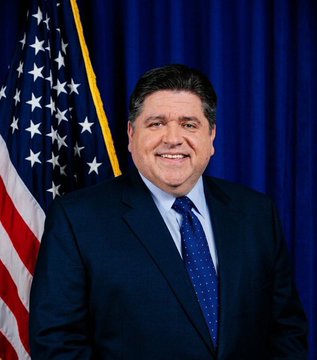 The image features a man wearing a suit standing against the backdrop of an American flag. He is smiling for the camera while posing for a portrait photo. The image also includes text that reads "BREAKING Illinois Gov. Pritzker signed a new 0.2% digital asset privilege tax on exchanges, $BTC and crypto transfers, and storage." This suggests that there might be some connection between the man in the suit and the recent executive order by the Illinois governor regarding cryptocurrency taxonomy.