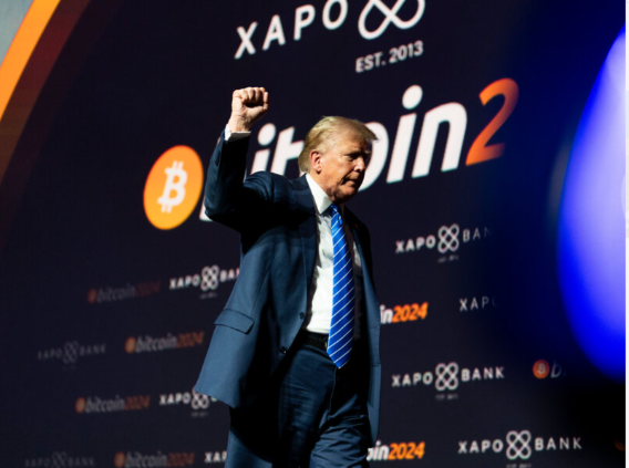 Donald Trump raising his fist on stage at the Bitcoin 2024 conference, with 'XAPO BANK EST. 2013' and 'Bitcoin 2024' logos visible on the backdrop.