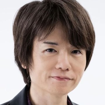 A close-up headshot of an Asian man with medium-length brown hair, smiling slightly against a white background.