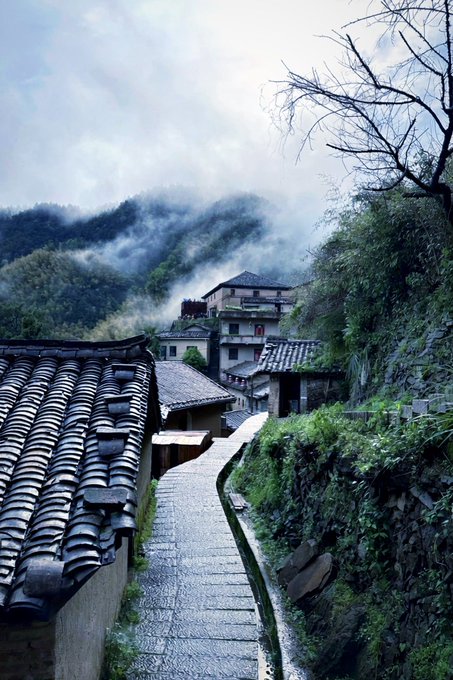 A misty mountain village path winds past traditional tiled rooftops, evoking the quiet journey toward a dream. The serene, winding road mirrors the crypto post's message—that a single connection, like one step down this path, can set everything in motion.