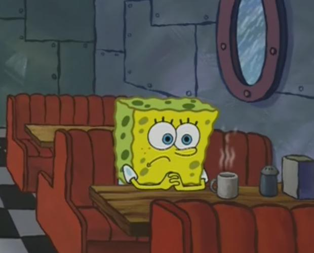 SpongeBob SquarePants sits alone at a red booth table in the Krusty Krab with a coffee mug, appearing concerned.