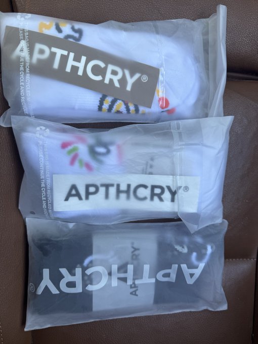 Three clear plastic packages labeled 'APTHCRY' are arranged on a brown leather surface.