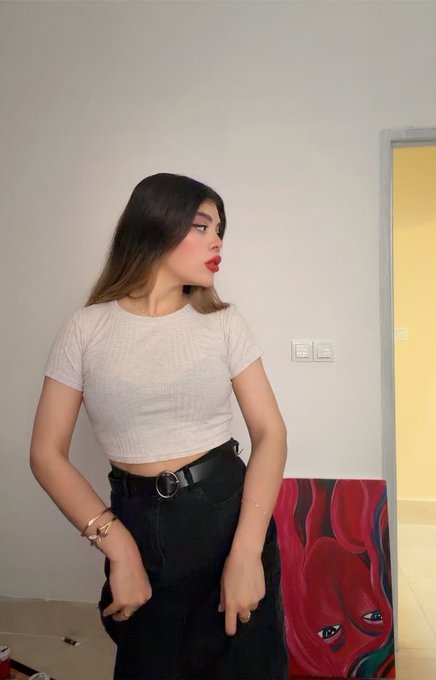 A young woman poses in a cream crop top and black belted pants beside her original artwork, a vibrant red and blue face painting displayed on the floor. The caption "SEREIN . 400 xtz" indicates the one-of-one NFT piece is being offered for 400 Tezos cryptocurrency.