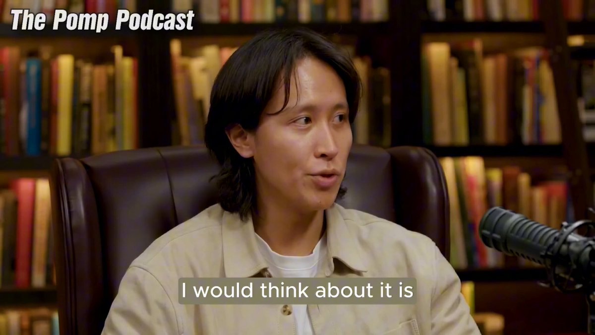 The image features a man sitting in an office chair, wearing a tan jacket, with a microphone attached to his ear. The background shows numerous bookshelves filled with various books of different sizes. The caption for the image reads "The PUMP Podcast", indicating that this is likely a podcast interview or discussion related to podcasts and their content.