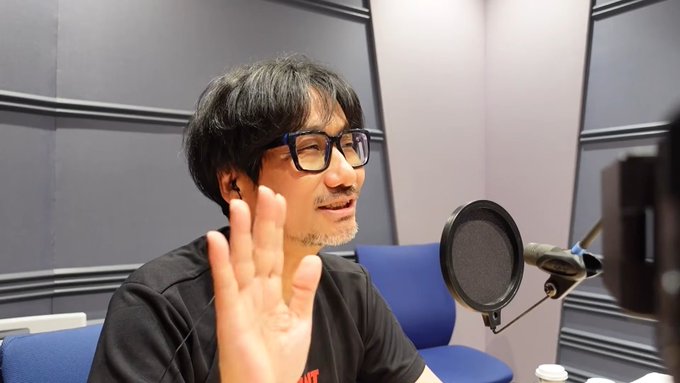 A man with glasses sits in a radio recording studio, gesturing with his hand while speaking into a microphone. The setting aligns with the post's mention of "KOJI10," likely referring to a radio show or podcast appearance.