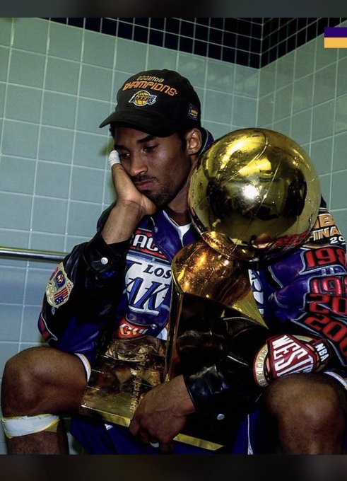 A reflective moment of triumph and exhaustion as the caption "Happy mid week champs it's a brand new day to conquer" is embodied by a championship athlete in a Los Angeles cap resting his head while cradling the golden Larry O'Brien championship trophy, surrounded by championship banners marking years like 19, 20, and 20.

The image visually echoes the motivational message by showing a champion in a quiet, contemplative moment with his ultimate prize—a reminder that greatness requires both relentless drive and intentional rest.